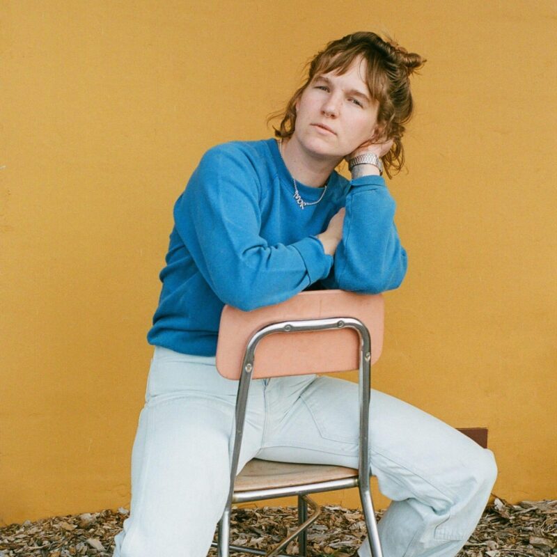 cody sitting on chair in blue shirt with yellow background