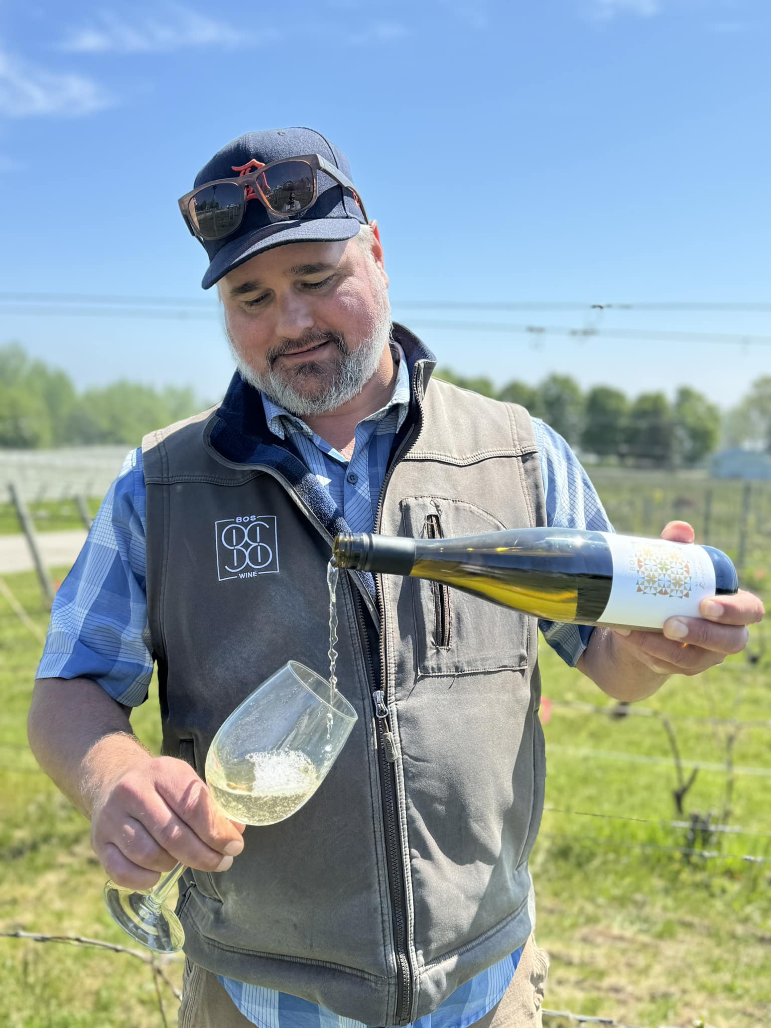 man pouring wine outside on his vineyard